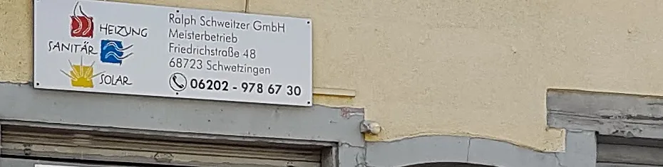 Das Firmenschild an der Hauswand: links die drei gemalten Zeichen für Heizung, Sanitär und Solar, rechts Name, Meisterbetrieb, Anschrift und Rufnummer.